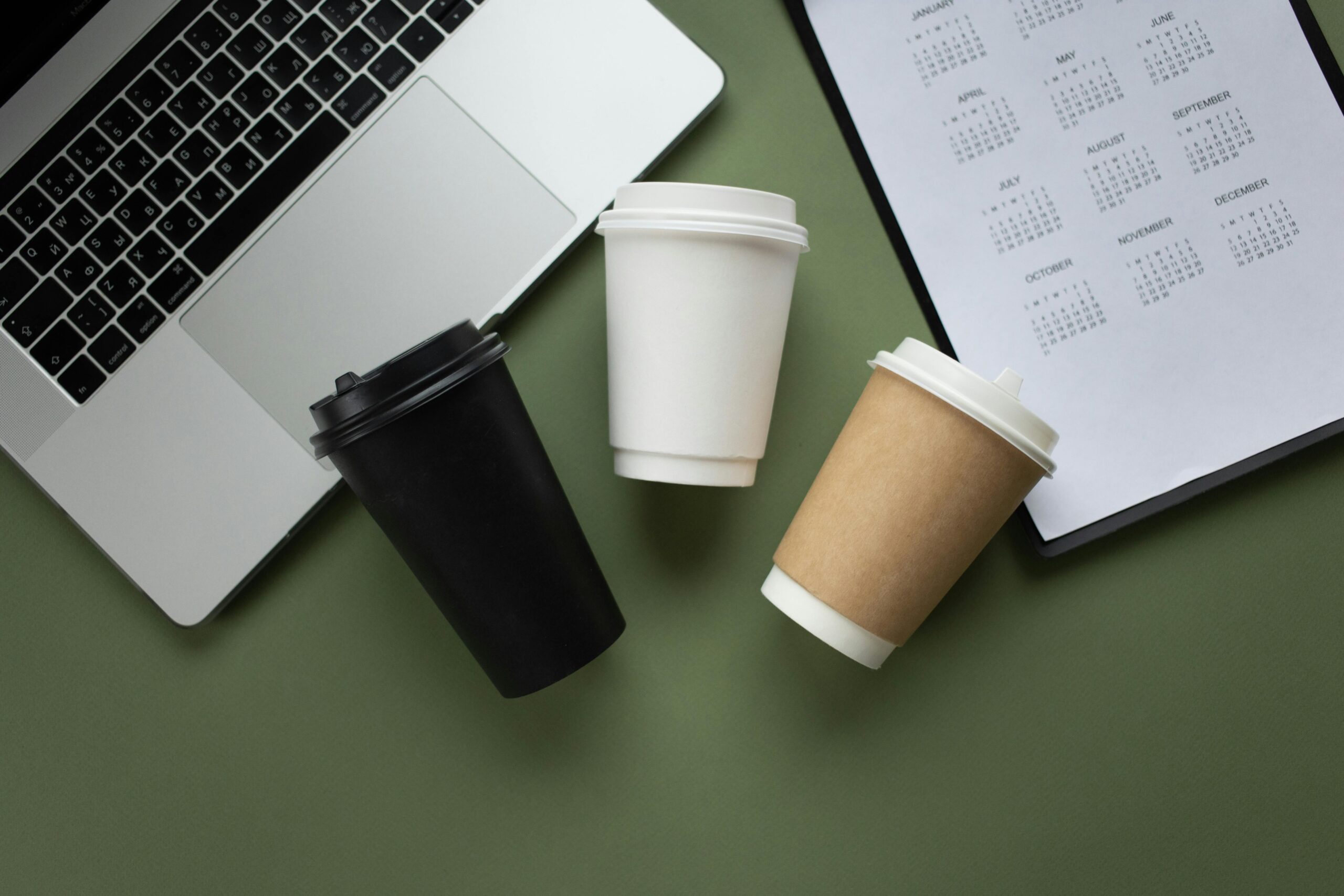 Stylish workspace with coffee cups, open laptop, and calendar, perfect for productivity.